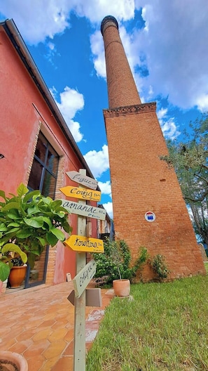 Ein Backsteinsschornstein, ein rotes Gebäude und Hinweisschilder.