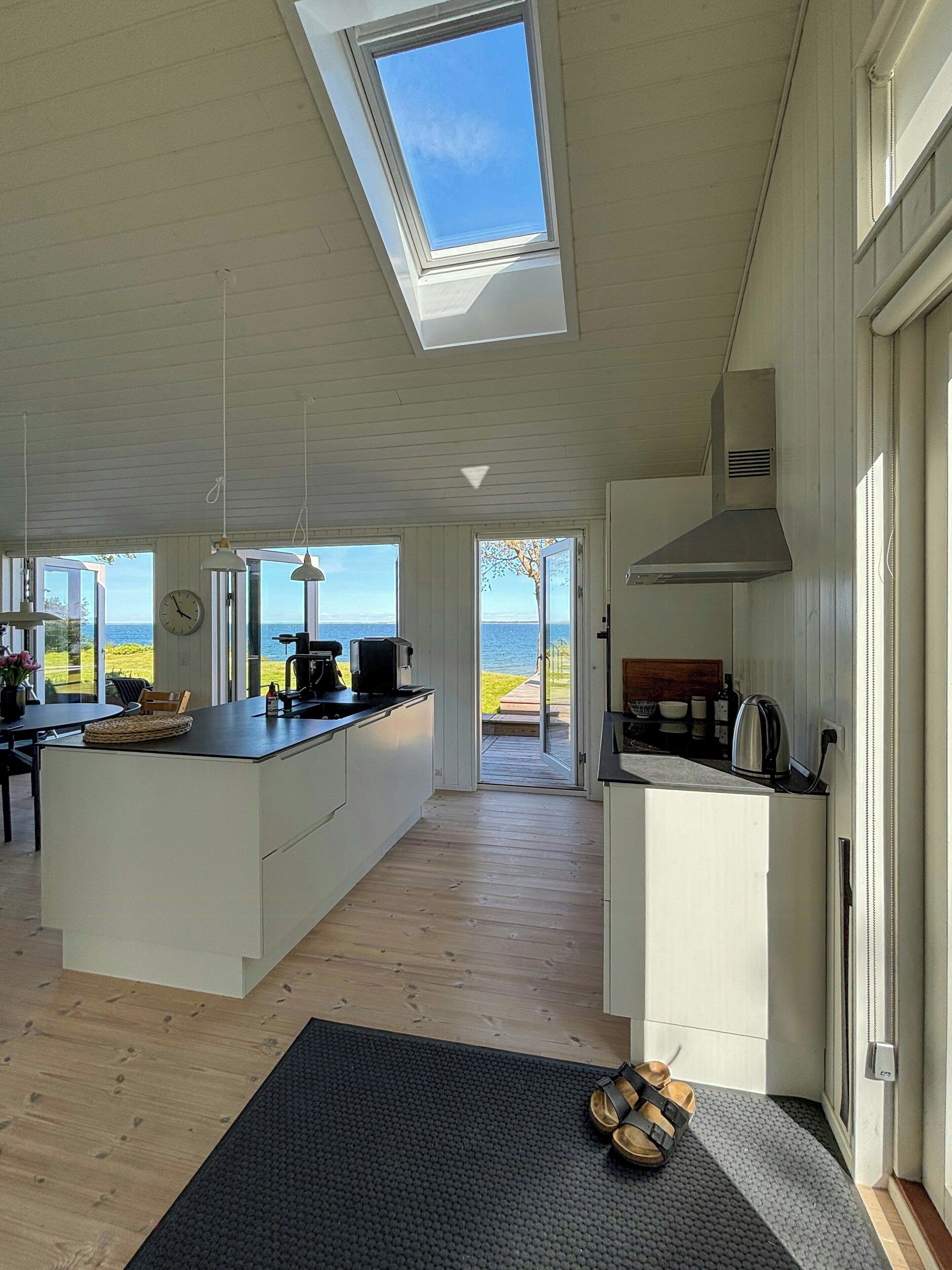A spacious kitchen with a large island, skylight, and a view of the sea.