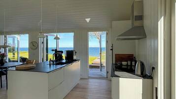 A spacious kitchen with a large island, skylight, and a view of the sea.