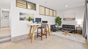 En moderne stue med et skrivebord, to sofaer, en plante og billeder på væggene.