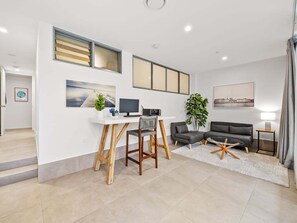 Ein modernes Wohnzimmer mit Schreibtisch, zwei Sofas, einer Pflanze und Kunstwerken an den Wänden.