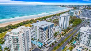 Ein Küstenhotel mit mehreren Hochhäusern, einem Strand und einer Straße mit parkenden Autos.