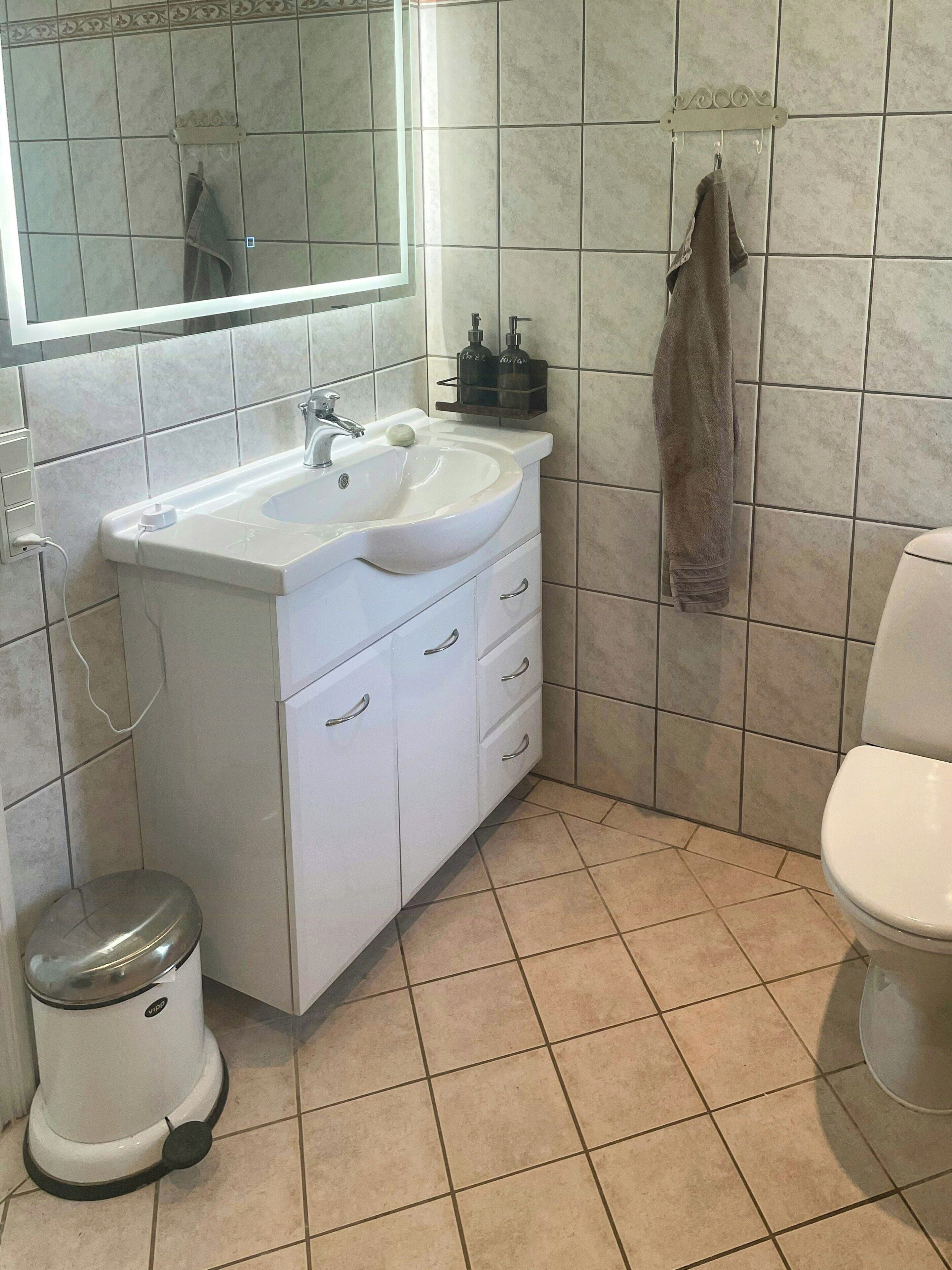 A bathroom with a white sink, mirror, and toilet.