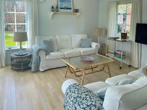A living room with a white sofa, a coffee table, a lamp, a TV, and a bookshelf. - Summer house by protected heathland in Ellinge (Højby)