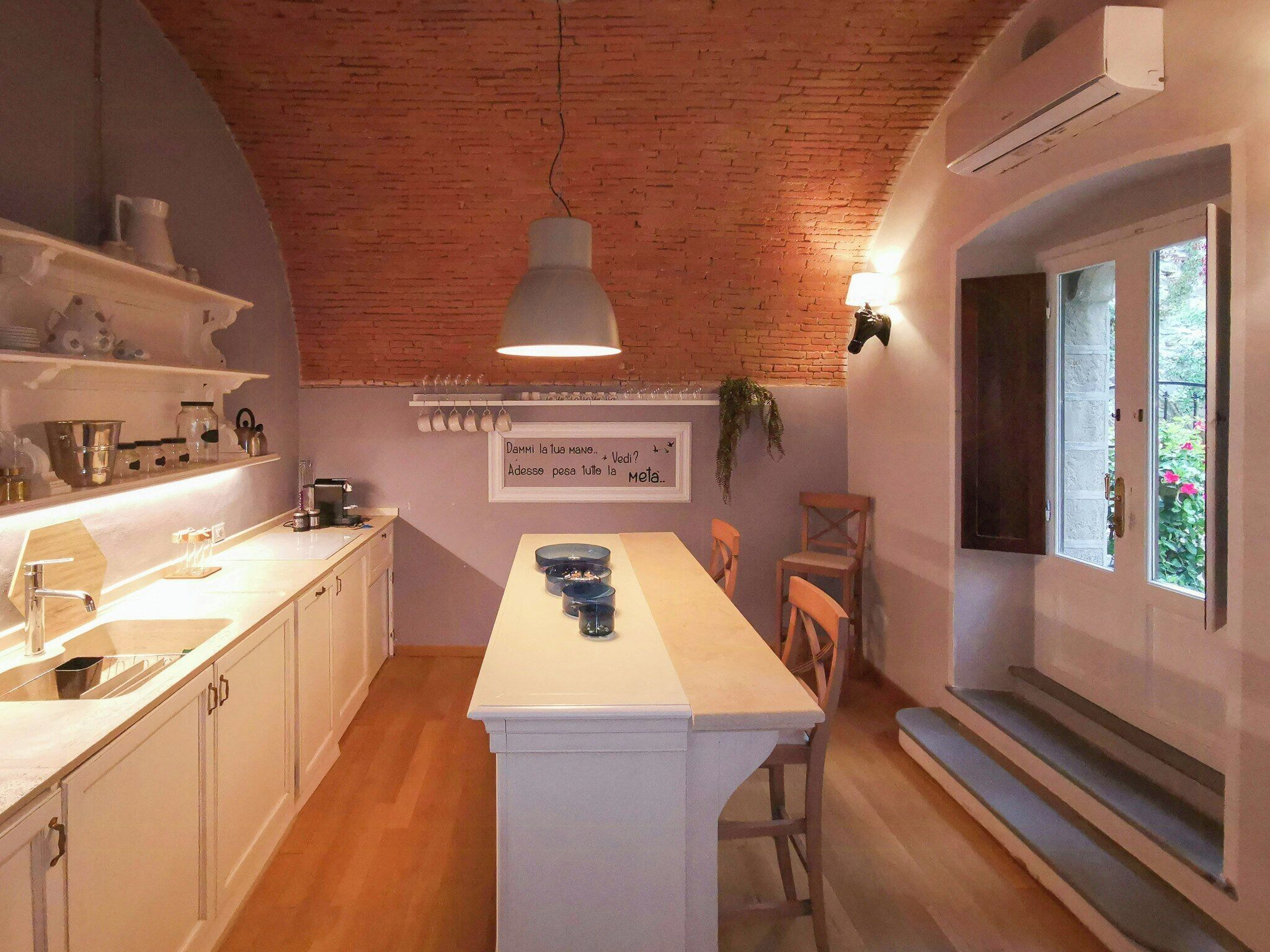 A kitchen with white cabinets, a central island, and a hanging light fixture.