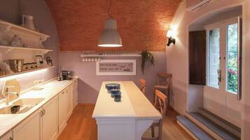 A kitchen with white cabinets, a central island, and a hanging light fixture.