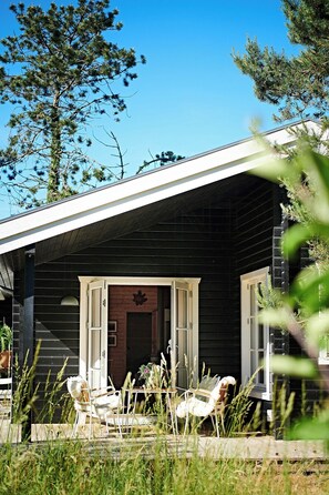 Ein Holzhaus mit Veranda, weißen Stühlen und einem Tisch.