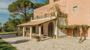 Ein Gebäude mit einer überdachten Terrasse, Sitzgelegenheiten im Freien und einem Garten.