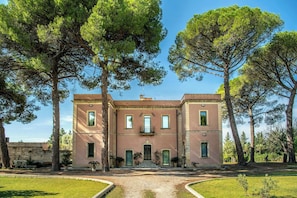 Un edificio a due piani con una facciata simmetrica, un ingresso centrale con gradini e un piccolo balcone al piano superiore.