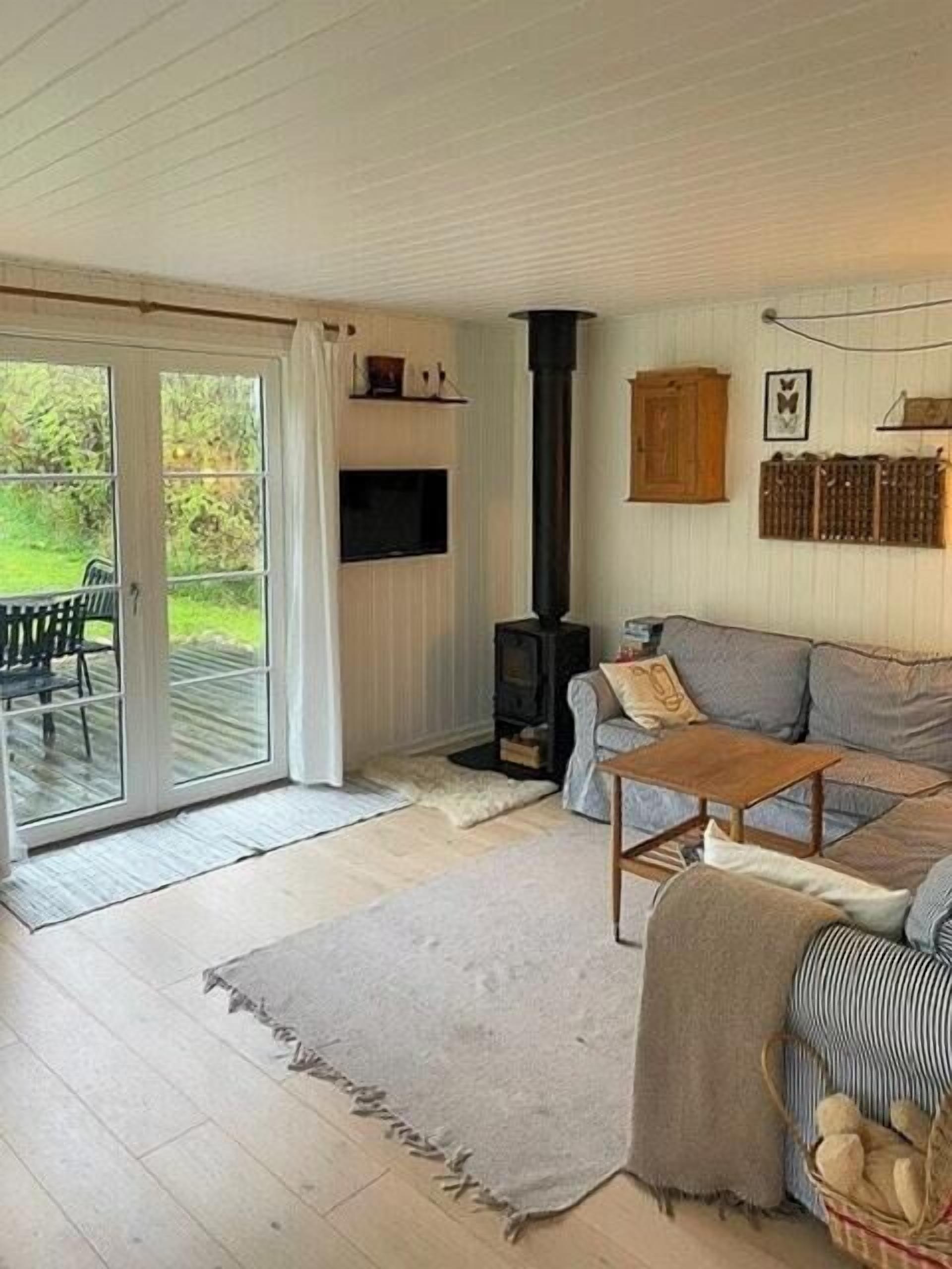 Un salon chaleureux avec un canapé, une table basse en bois, une cheminée et une porte-fenêtre coulissante donnant sur une terrasse.
