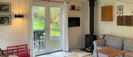 Een gezellige woonkamer met een open haard, een bank, een salontafel en een rode fauteuil.
