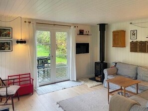 Een gezellige woonkamer met een open haard, een bank, een salontafel en een rode fauteuil.