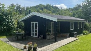 Ein kleines, dunkel gefärbtes Haus mit Veranda, Tür und Fenster.