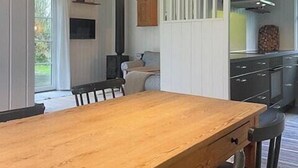 Ein Essbereich mit einem Holztisch und Stühlen, einer Pendelleuchte und Blick in die Küche.