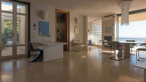 Um quarto espaçoso com uma janela grande, uma escrivaninha, uma cadeira e uma mesa.