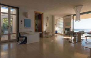 Ein geräumiges Zimmer mit großem Fenster, Schreibtisch, Stuhl und Tisch.