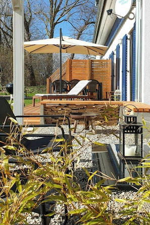 An outdoor patio with a grill, seating, and a wooden deck. - Family home near beach in Altefähr on Rügen (Altefähr)