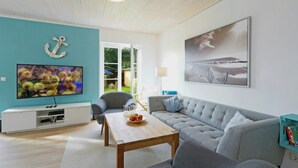 Ett vardagsrum med en TV, en soffa, ett soffbord och konstverk.