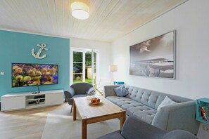 A living room with a TV, sofa, coffee table, and artwork. - Family home near beach in Altefähr on Rügen (Altefähr)