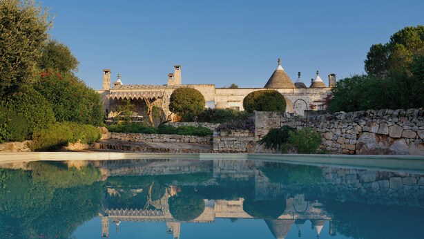 Ein Pool, der einen Steinbau mit Bogenfenstern und einer Kuppel reflektiert.