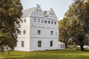 Ein großes, weißes, mehrgeschossiges Gebäude mit symmetrischer Architektur, großen Fenstern und einem markanten Kreuz auf dem Dach.