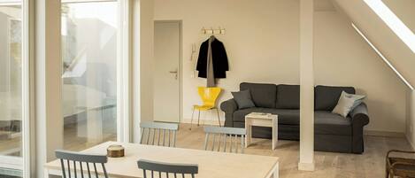 A modern living space with a dining area, a sofa, and a coat rack.