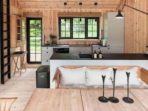 A wooden interior with a kitchen, dining area, and a view through a window. - Serenety with a sea view amidst preserved nature (Kalundborg)