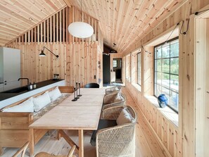 A wooden interior with a long dining table, chairs, a kitchen area, and large windows. - Serenety with a sea view amidst preserved nature (Kalundborg)