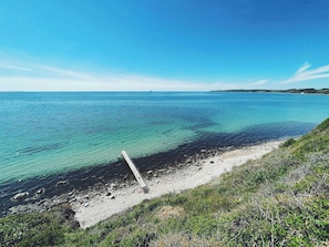 Un paisaje costero con aguas azules cristalinas, una costa rocosa y una zona con césped.