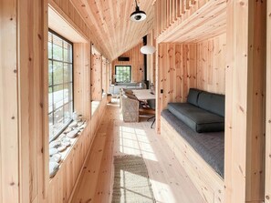 A wooden interior with a sofa, a dining area, and a kitchen. - Serenety with a sea view amidst preserved nature (Kalundborg)