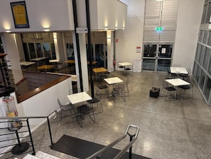 A hotel lobby with multiple tables and chairs, a staircase, and a sign indicating the location of toilets. - Eatons Hotel (Muswellbrook)