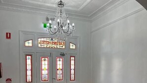 A room with a wooden floor, white walls, a chandelier, and stained glass doors. - Eatons Hotel (Muswellbrook)