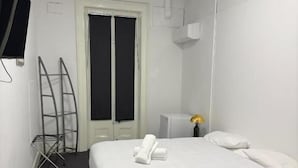A hotel room with a bed, a TV, a door, and a window. - Eatons Hotel (Muswellbrook)