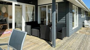 A covered outdoor seating area with wicker furniture and a wooden deck. - Idyllic holiday home charm in Nr. Lyngby (Løkken)