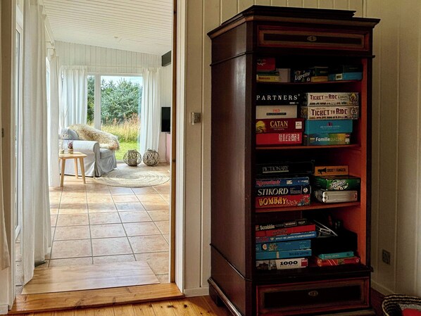 A room with a wooden floor, a sofa, a coffee table, and a bookshelf filled with board games.