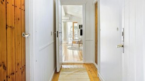 A hallway with wooden doors, a white ceiling, and a view into a room with a table and chairs. - Idyllic holiday home charm in Nr. Lyngby (Løkken)