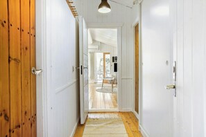 A hallway with wooden doors, a white ceiling, and a view into a room with a table and chairs. - Idyllic holiday home charm in Nr. Lyngby (Løkken)