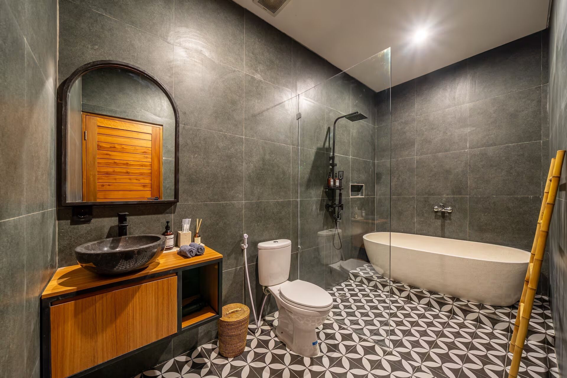 Un baño moderno con un espejo grande, un tocador de madera, un lavabo, un inodoro, una ducha y una bañera.