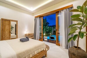 A bedroom with a bed, bedside table, and a view of an outdoor pool area. - Dasha 2 Villa (Kerobokan)