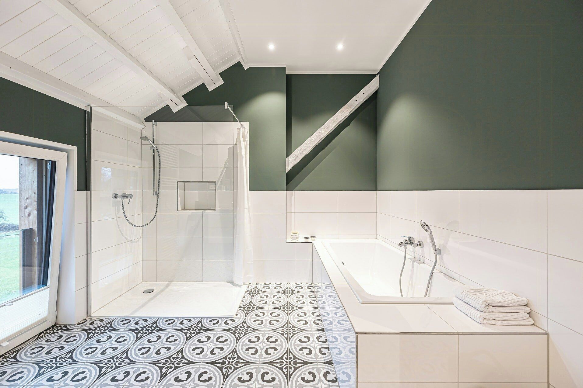Une salle de bain moderne avec douche, baignoire et carrelage au sol à motifs.