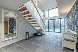 Ein geräumiges Zimmer mit moderner Treppe, großem Fenster und einer Wand mit Muster.