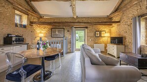 A rustic stone interior with a dining area, sofa, and TV. - Charming mas with medieval church views (Sainte Croix)