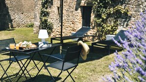An outdoor dining area with a table set for two, a lamp, and a tray with food and drinks. - Charming mas with medieval church views (Sainte Croix)