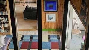 A room with a wooden interior, a television mounted on the wall, a bookshelf, a colorful rug, and a chair. - Artist's dream in scenic Södermanland (Gnesta)
