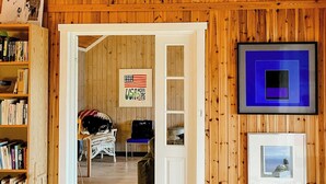 A room with wooden walls, a clock, a framed USA flag, a blue framed artwork, and a door leading to another room. - Artist's dream in scenic Södermanland (Gnesta)