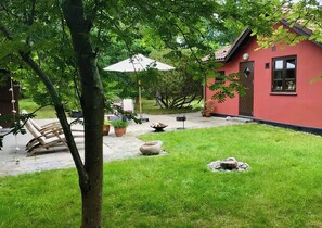 Ein rotes Gebäude mit Terrasse, Sitzgelegenheiten im Freien und einem Feuerkorb.
