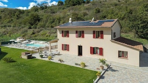 Ein zweistöckiges Haus mit Swimmingpool, Solaranlage und Garten.