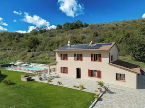Ein zweistöckiges Haus mit Swimmingpool, Solaranlage und Garten.