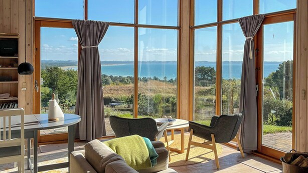 Una habitación amplia con un ventanal grande, un sofá, una mesa y un televisor.