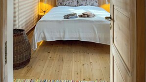 Un dormitorio con paneles de madera, una cama, dos lámparas de noche, una ventana y una puerta.